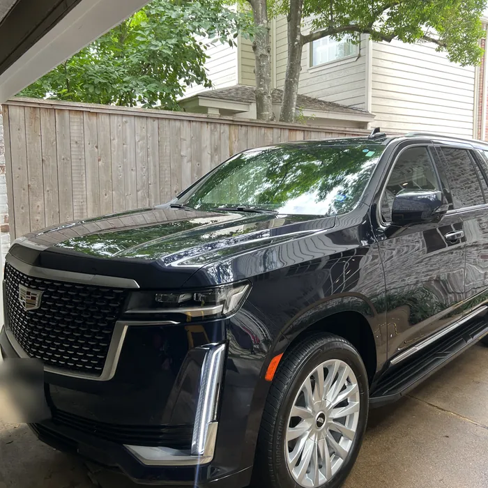 Dark blue Cadillac Escalade after a detail, in a driveway under trees