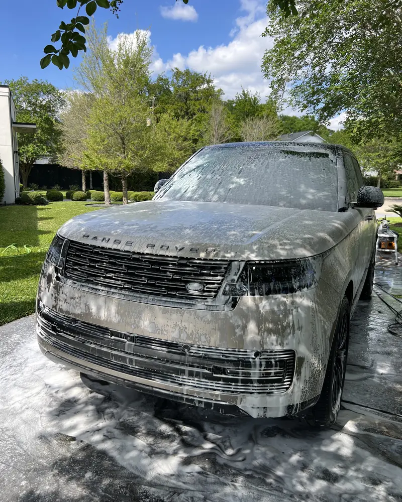 Range Rover covered in foam during the pre-wash, parked in the shade on the client's driveway