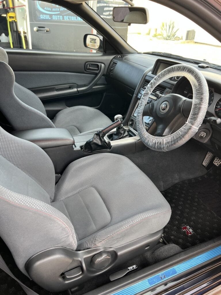 Nissan Skyline GT-R original cloth seats and carpet after an Azul collector-vehicle interior preservation detail, with the Azul van parked outside