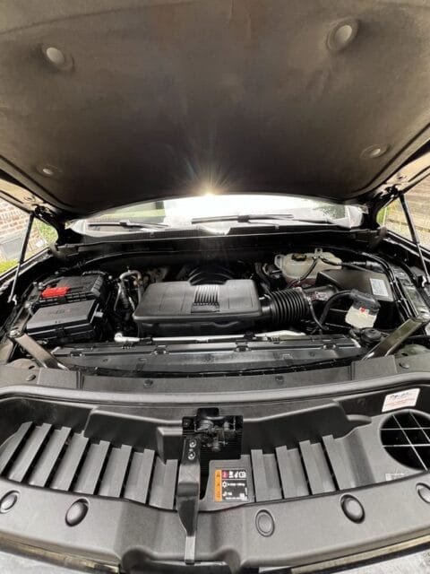 After: the same Cadillac Escalade engine bay cleaned, with plastic covers dressed to a satin finish