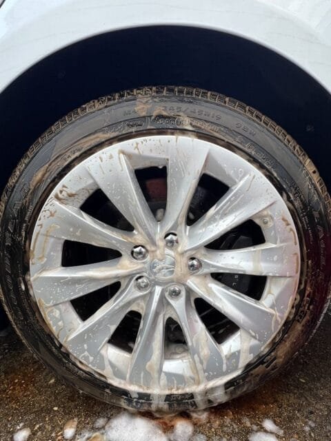 During the wash: Tesla wheel and tire covered in cleaner lifting baked-on brake dust