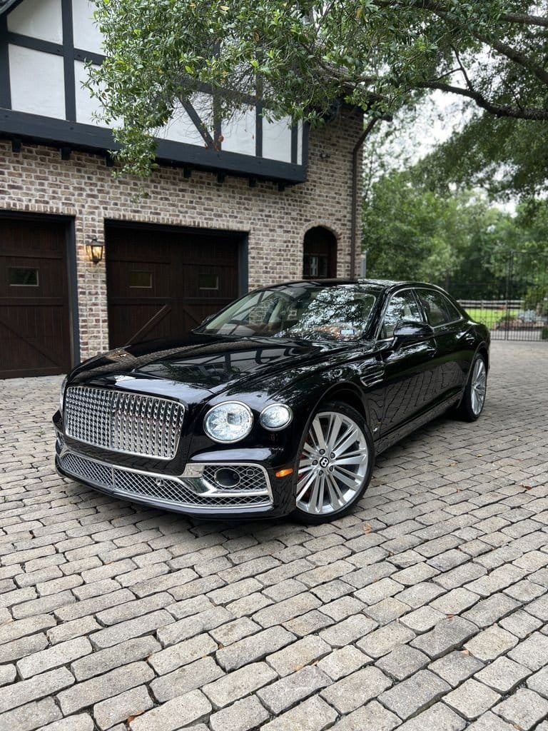 Black Bentley Flying Spur with glossy paint reflecting the trees, parked on a cobblestone driveway after an Azul exterior detail