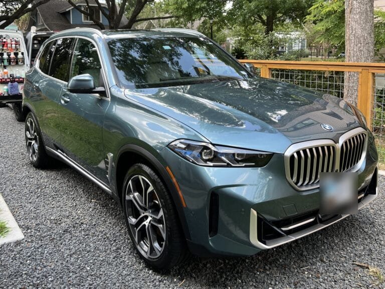 BMW X5 after a mobile Full Detail in a Houston driveway, with the Azul Auto Detailing van and products behind it