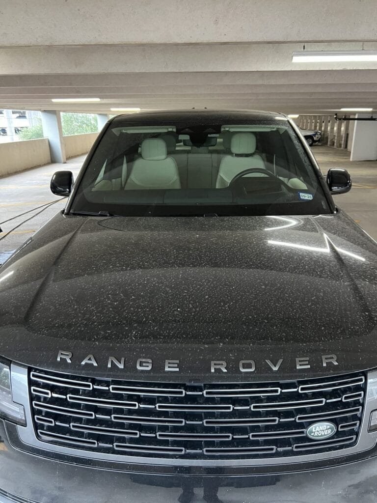 Range Rover hood and windshield covered in dust and debris before a Full Detail in a Houston parking garage