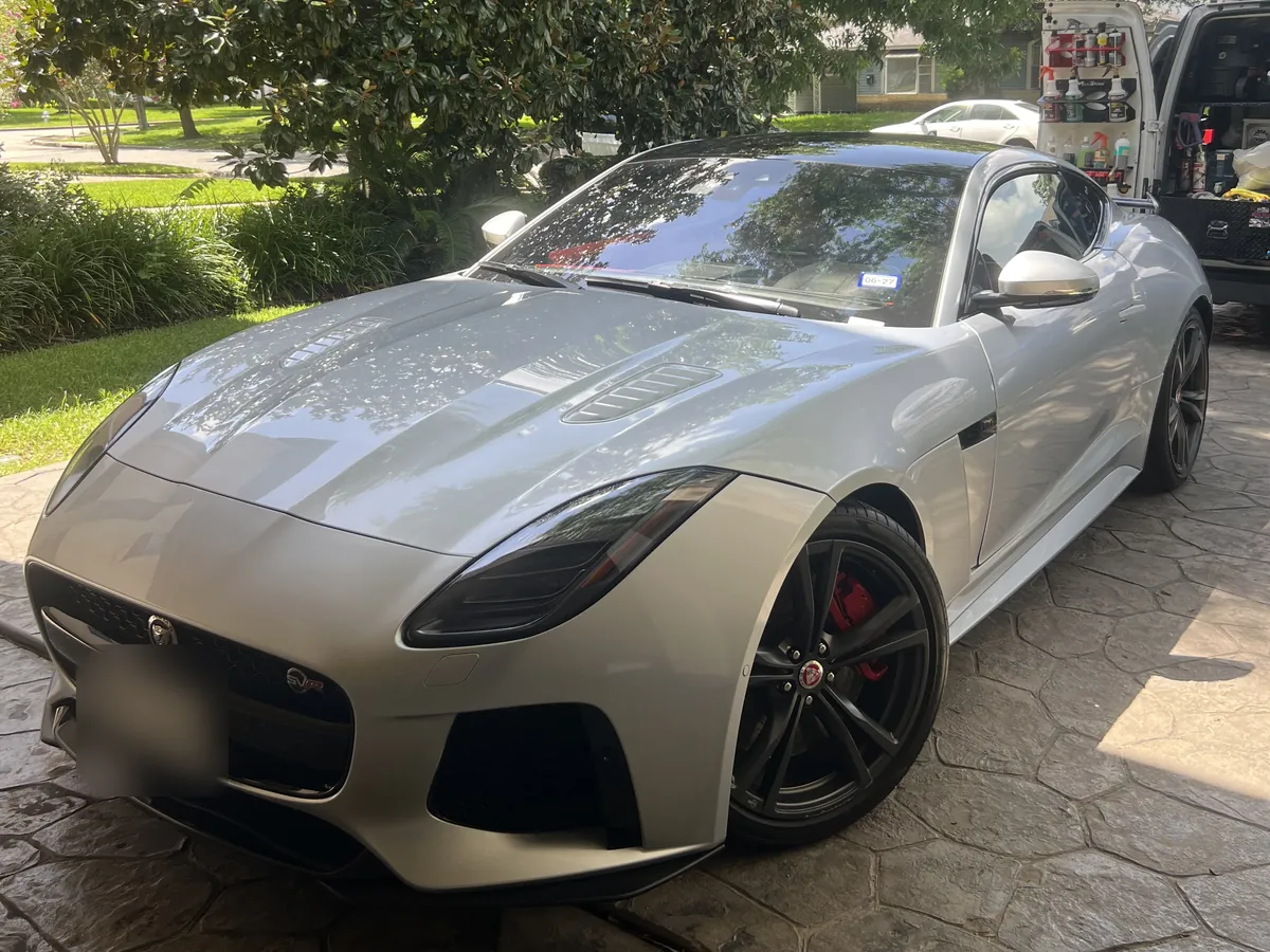Silver Jaguar F-Type SVR after an Azul detail, on a stamped-concrete driveway in Bellaire, with the Azul van behind it