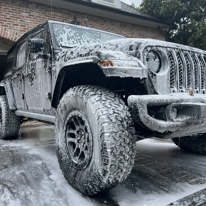 Jeep Wrangler covered in wash foam during a hand wash in a River Oaks driveway