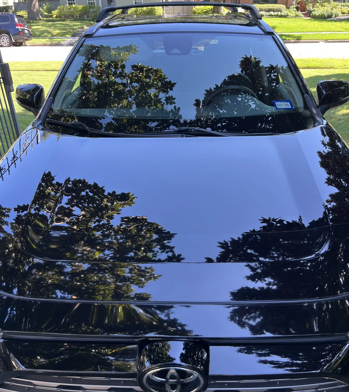Black Toyota RAV4 hood after a Two-Stage Paint Correction, with sharp tree reflections