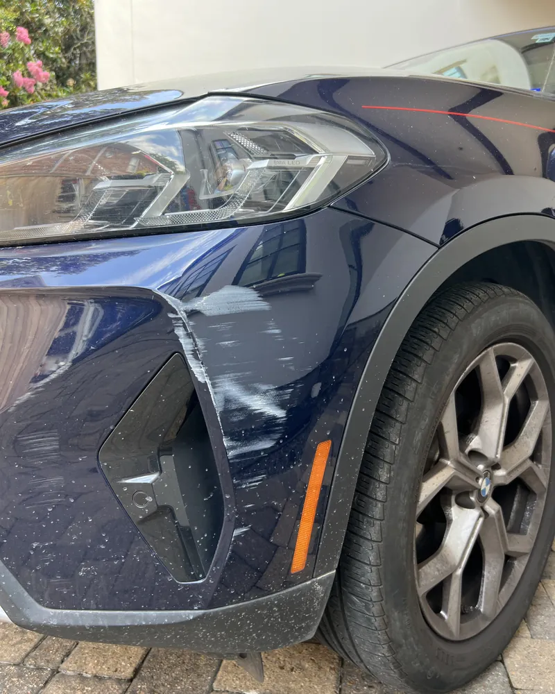 White paint transfer scuffs on a dark blue BMW X3 front bumper