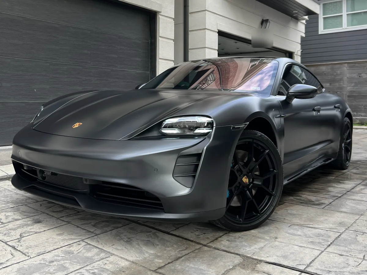Satin black Porsche Taycan after an Azul detail, on a stamped-concrete driveway at a townhome near the Galleria
