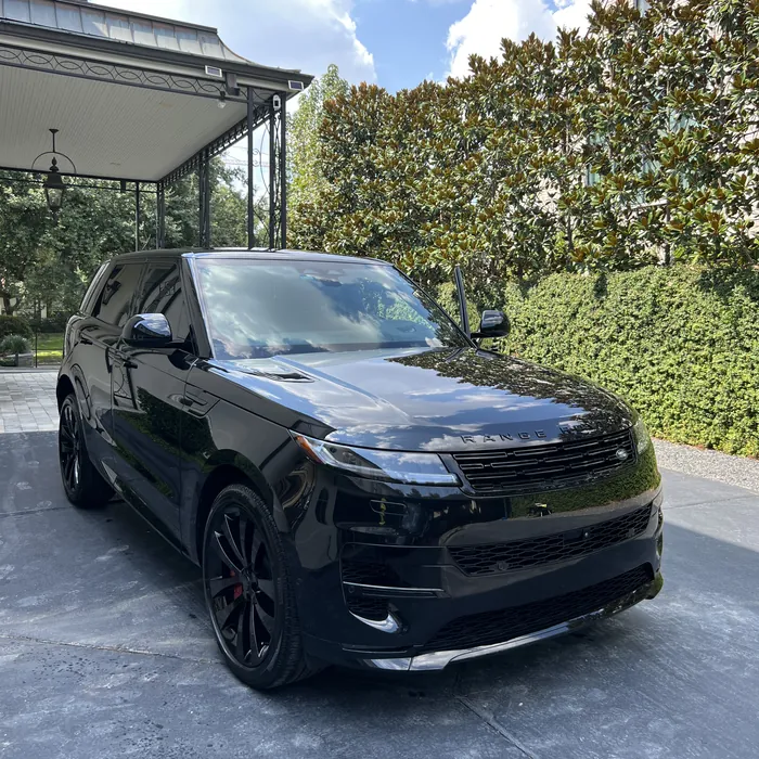 Black Range Rover Sport after a detail, beside a carport and magnolia hedge