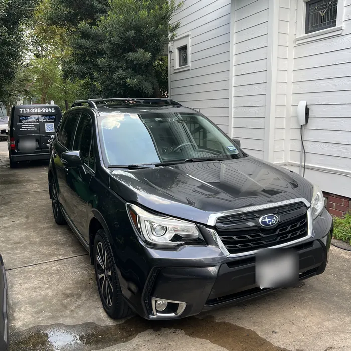 Dark gray Subaru Forester after a detail in a Heights driveway, with the Azul van behind it