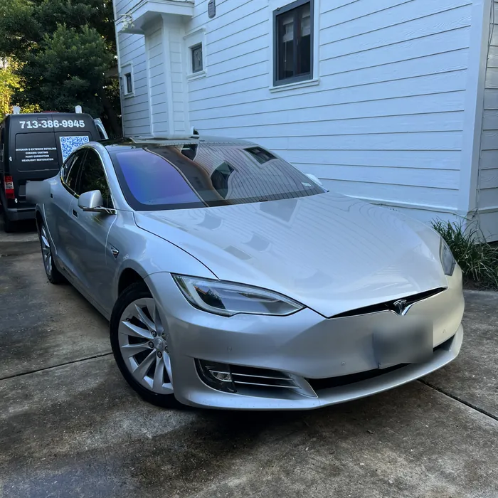Silver Tesla Model S after a detail beside a white Heights house, with the Azul van behind it