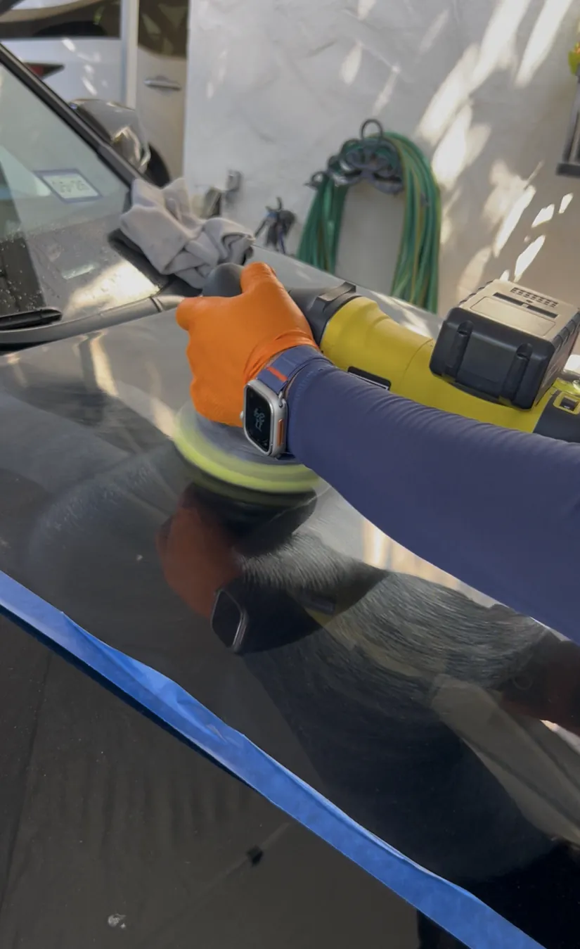 Detailer machine polishing the hood of a black Toyota RAV4 during paint correction