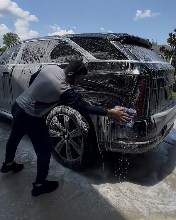 Nassim hand washing a black SUV during a mobile detail in Houston