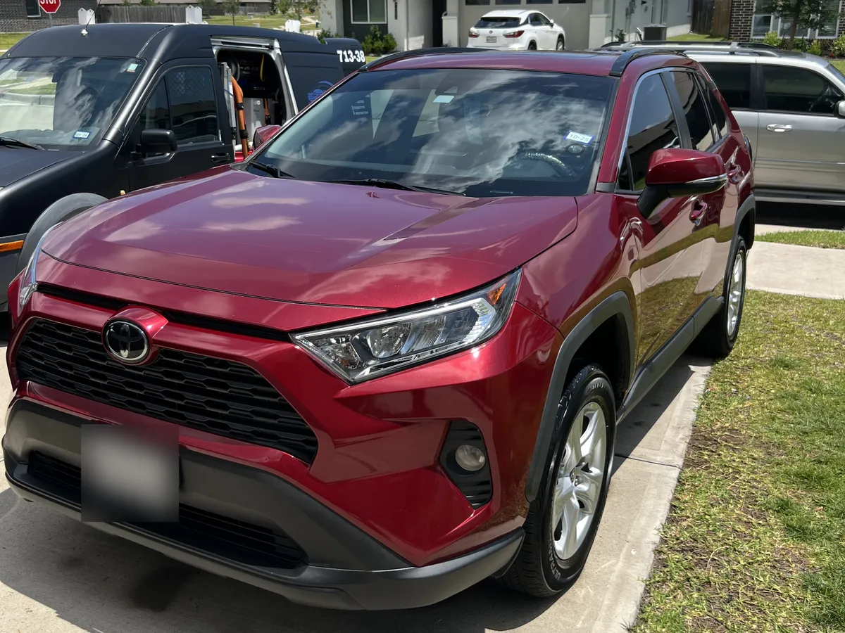 Red Toyota RAV4 after an Azul mobile detail, in a Katy driveway with the Azul van behind it